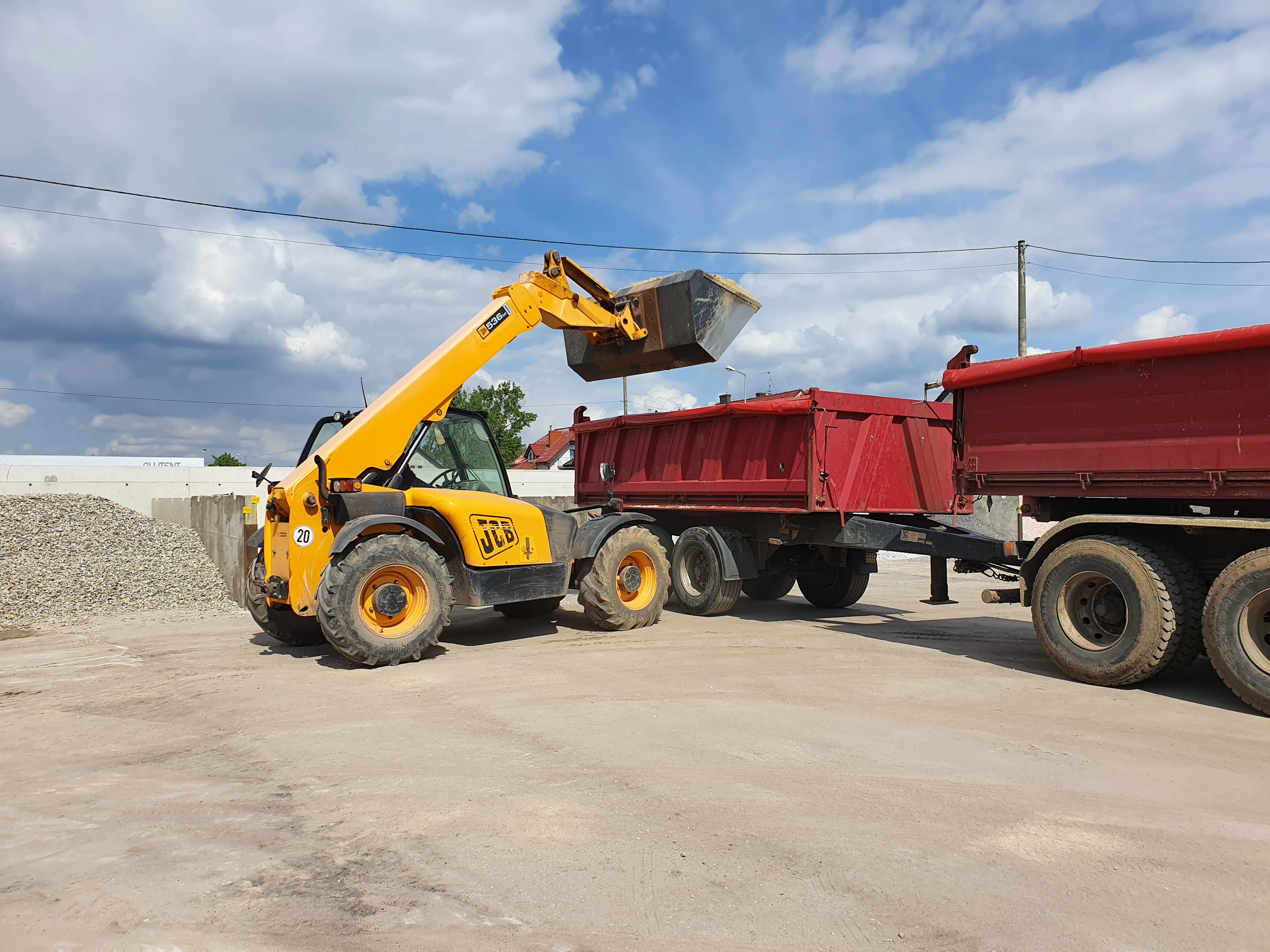 Ładowarka JCB ładująca wywrotkę na placu STENAR